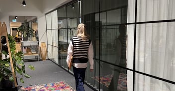 Nainen kävelee kokoushuoneeseen laptop kädessä