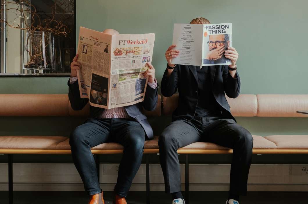 Kaksi ihmistä lukemassa sanomalehteä yhteisöllisissä toimistotiloissa Innovation Home Kamppi, Helsingissä